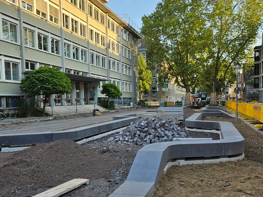 Zu sehen ist ein Projekt der Städtebauförderung in einer Innenstadt. Noch ist die Straße im Bau aber man erkennt schon geschwungene Mauern.