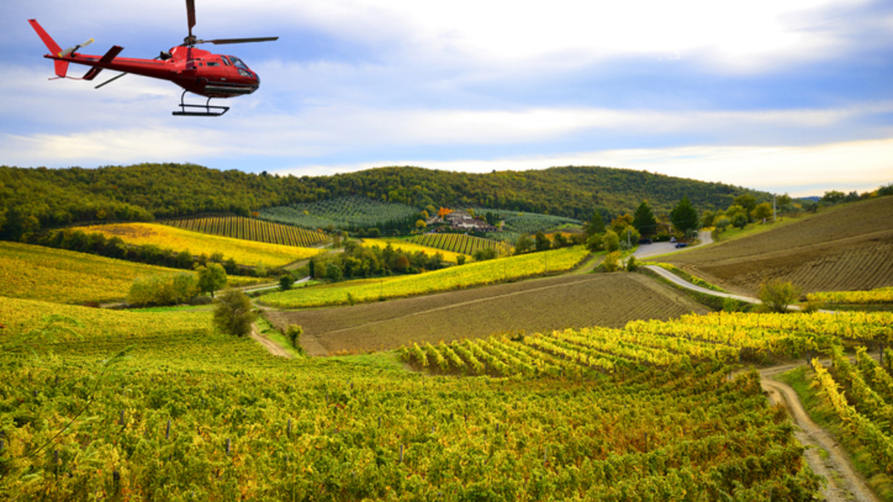 Ein roter Hubschrauber fliegt über die Weinberge um die Pflanzen zu spritzen
